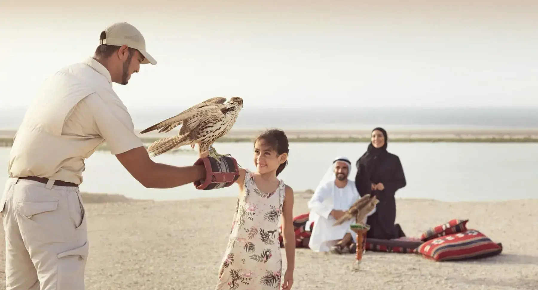 A falconer helps a young girl hold the bird