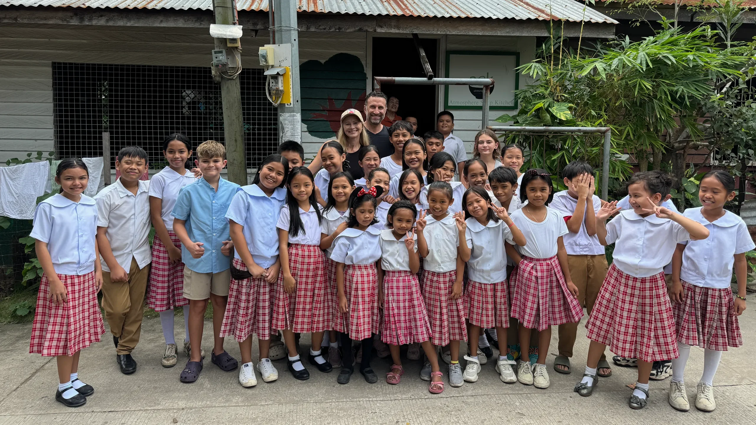 Phil and Erin Lockwood with Colt and a group of schoolchildren in uniform in the Philippines