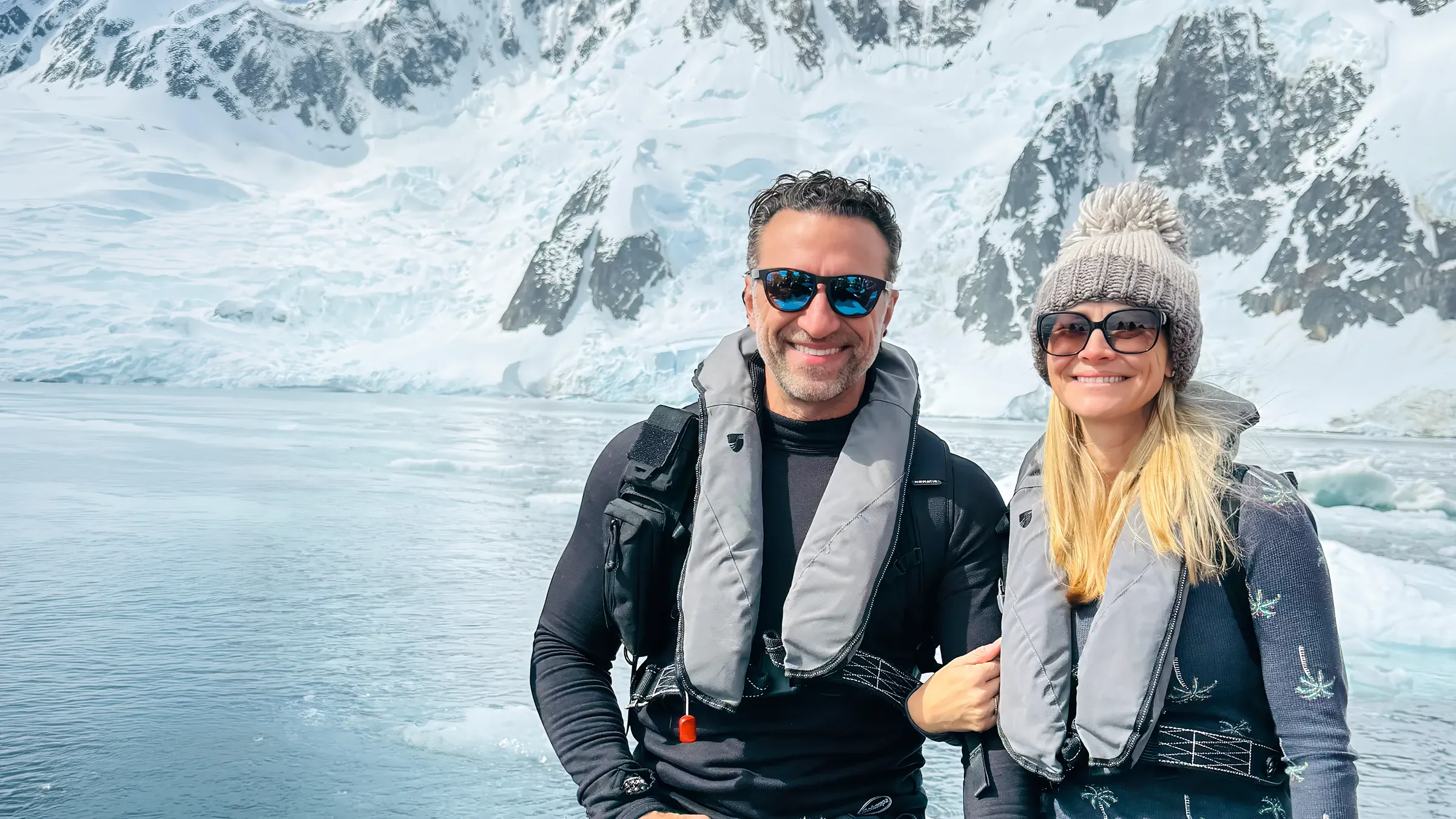Phil and Erin in life vests on a Zodiac below an Antarctic glacier