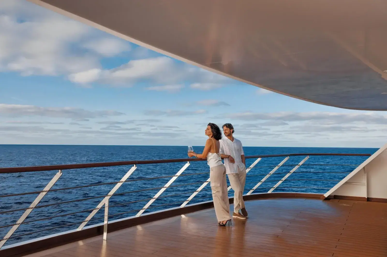 A couple stand on the aft deck of The Atlas Ocean Voyages' Atlas Adventurer sailing yacht