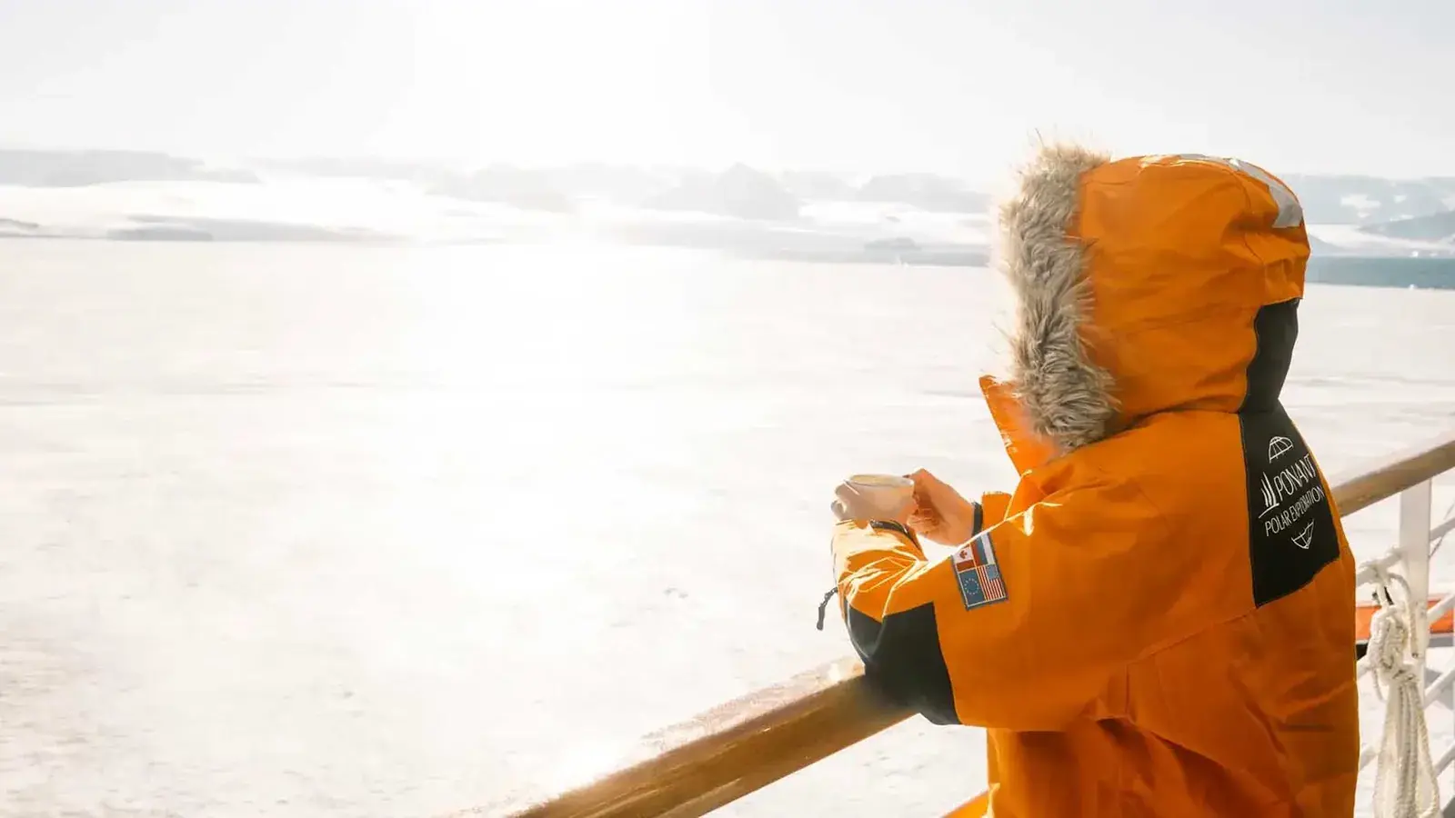 Passenger in parka gazing from Le Commandant Charcot deck in polar region