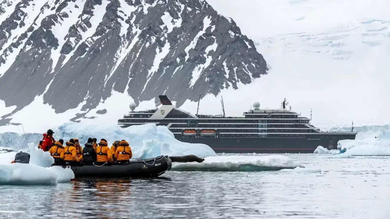 Seabourn Venture in Antarctica with a zodiac full of passengers in the foregound