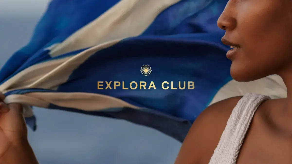 A woman waves an Explora Journeys flag