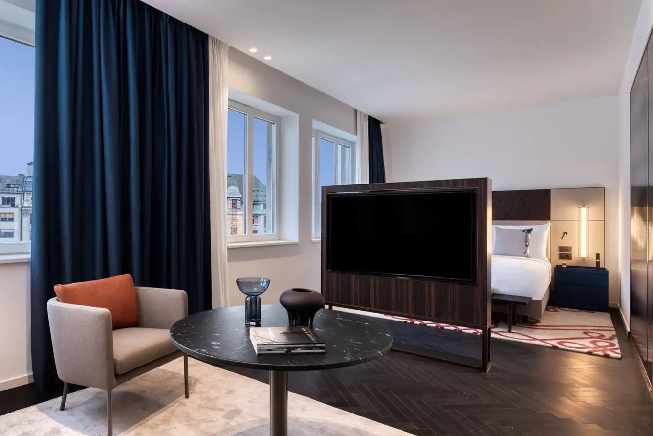 A Contemporary Studio Suite at the Dorothea Hotel: sitting area with a marble table, a TV partition and the bed beyond