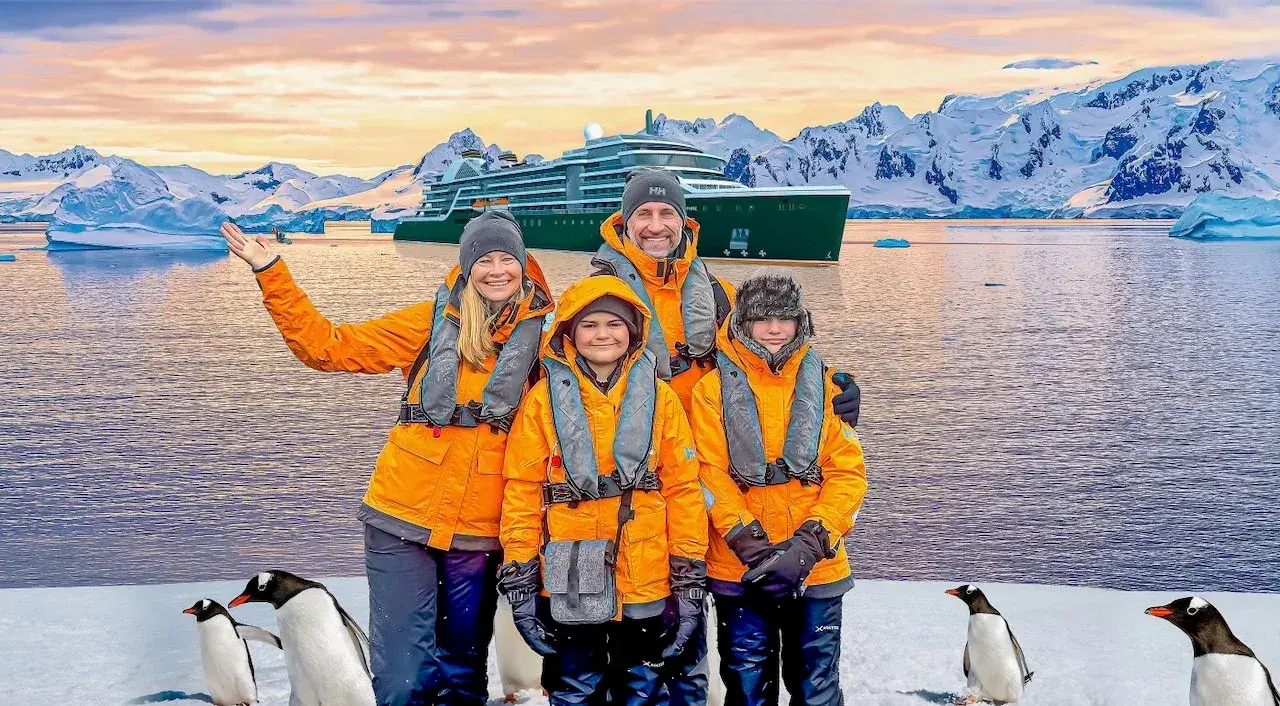 The Lockwood family standing in Antarctica with a cruise ship behind