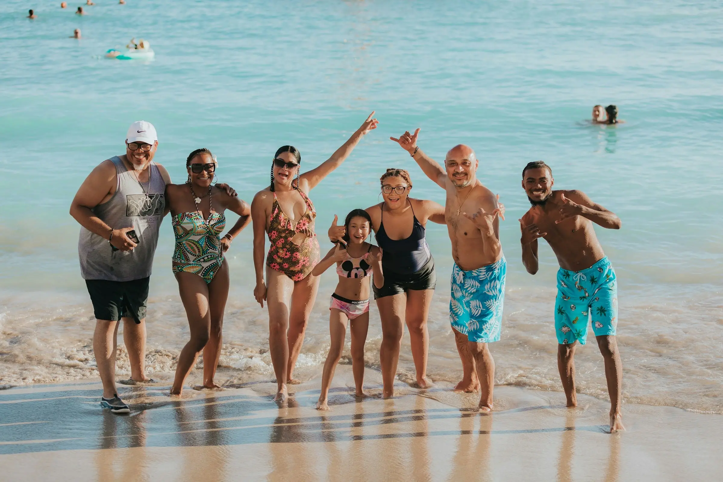 A three-generation family posing in the surf on a tropical beach