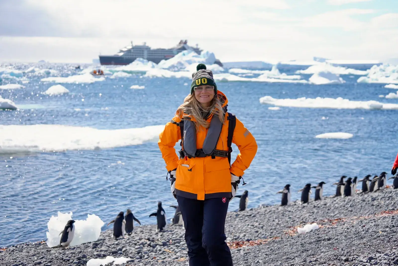 Erin Lockwood standing on the shore of Antarctica, surrounded by penguins