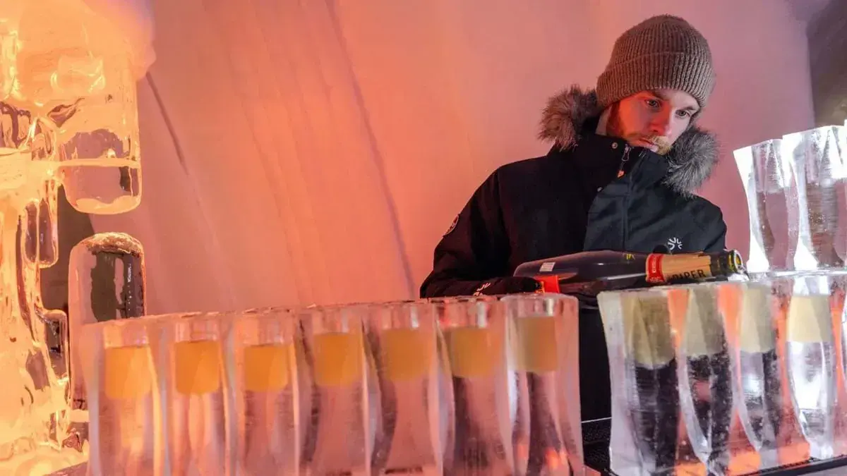 A bartender pours champagne into ice glasses at Hôtel de Glace