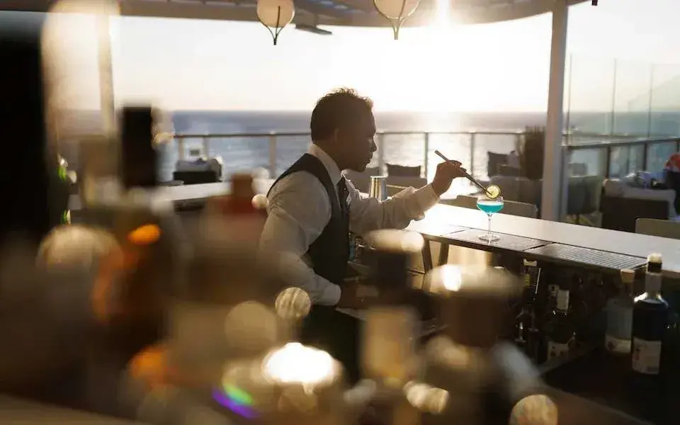 A bartender makes drinks at an outdoor bar on a Silversea cruise ship