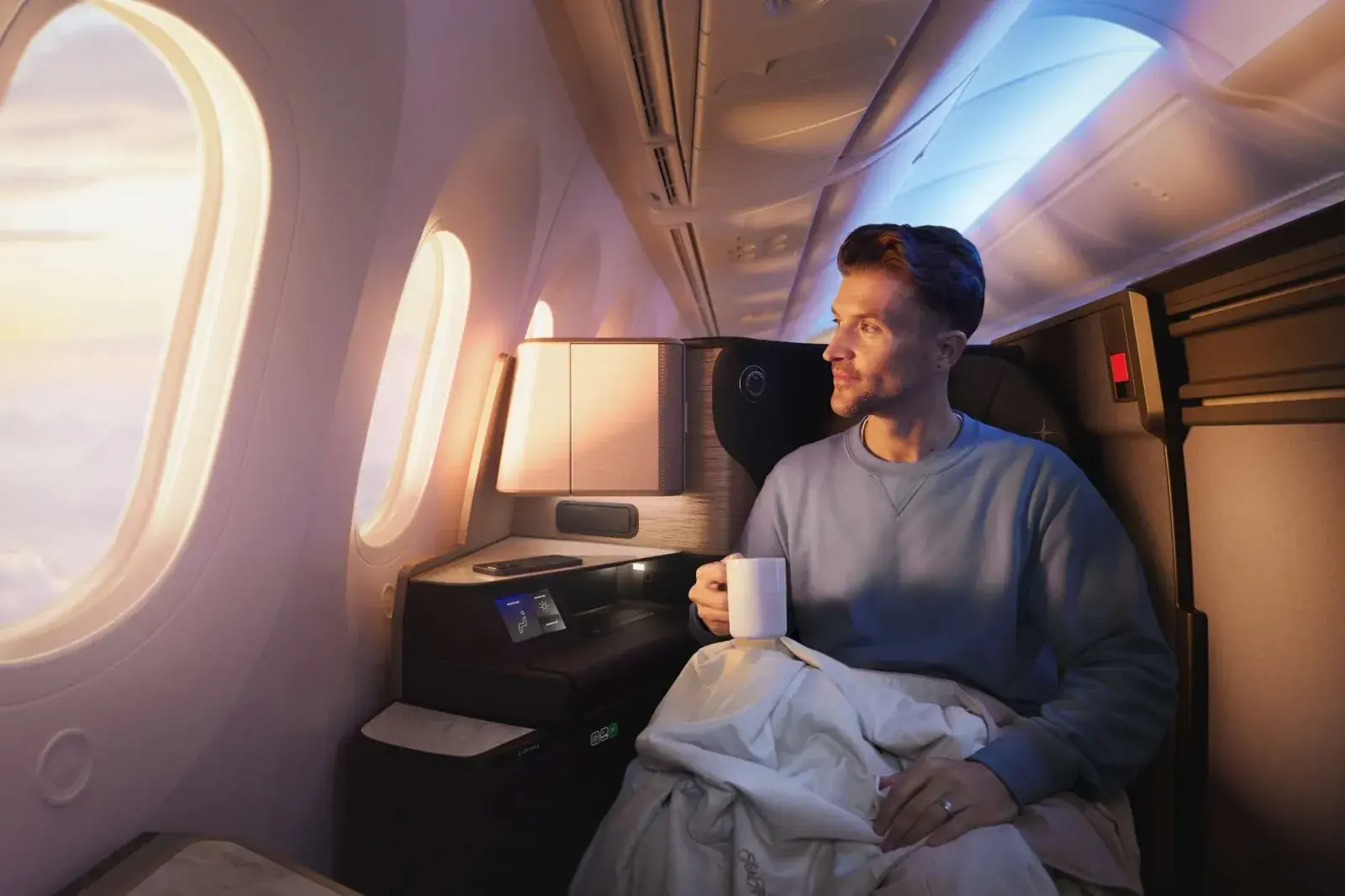 A man looks out at the sunrise from United Airlines Polaris Studio business class seating
