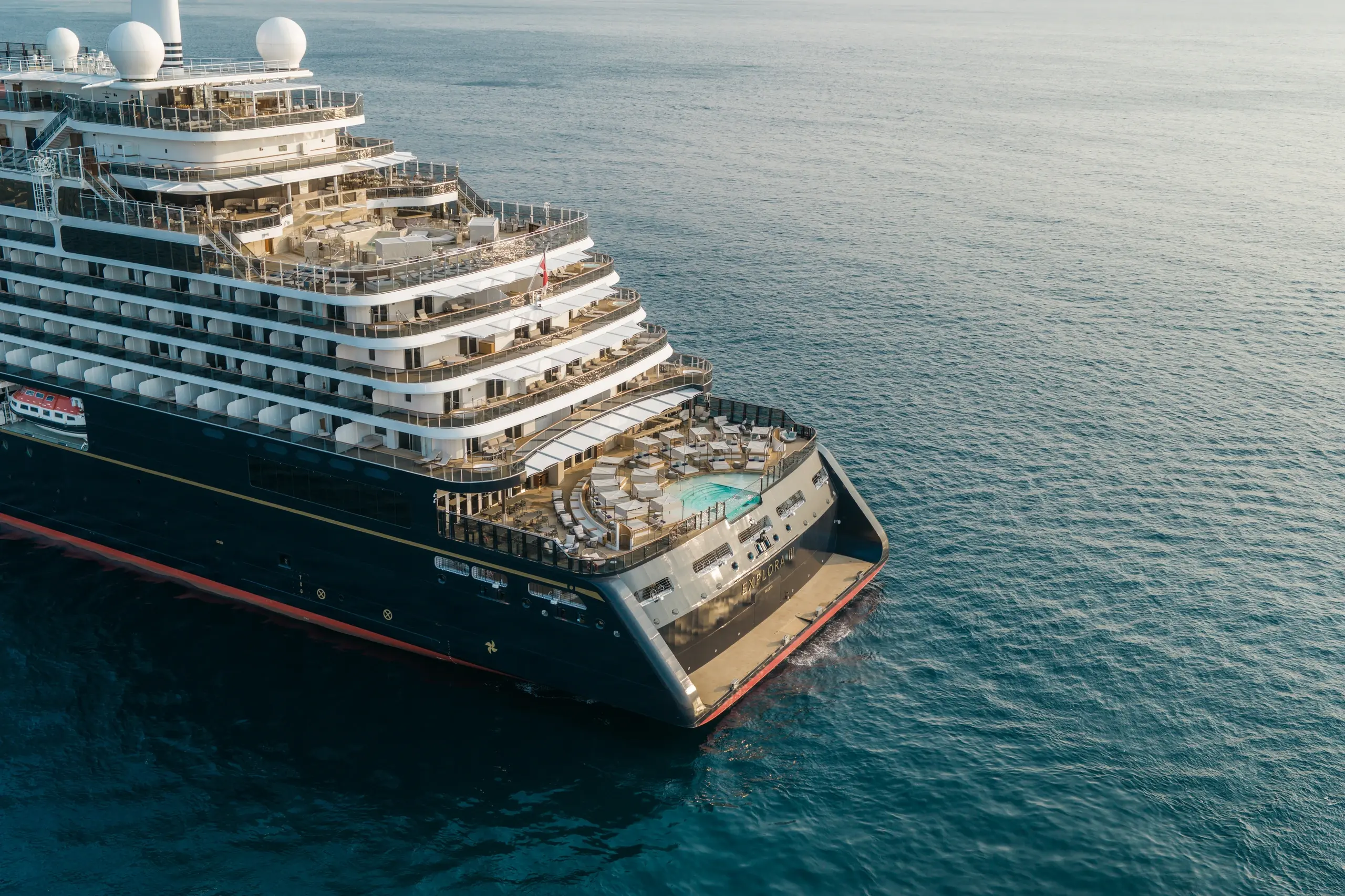 Aerial view of Explora III at sea, with its aft pool deck and tiers of suite terraces