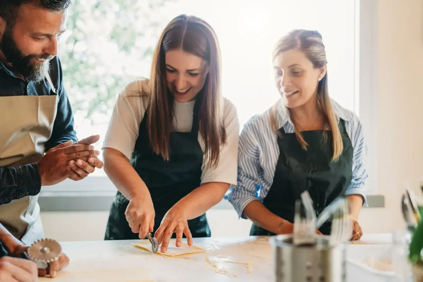 A man and two woman make pasta together