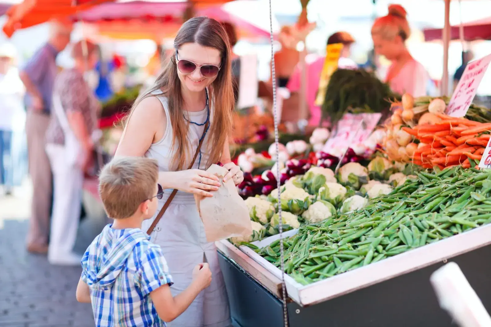 A mother and son shop for vegetables at a farmers market