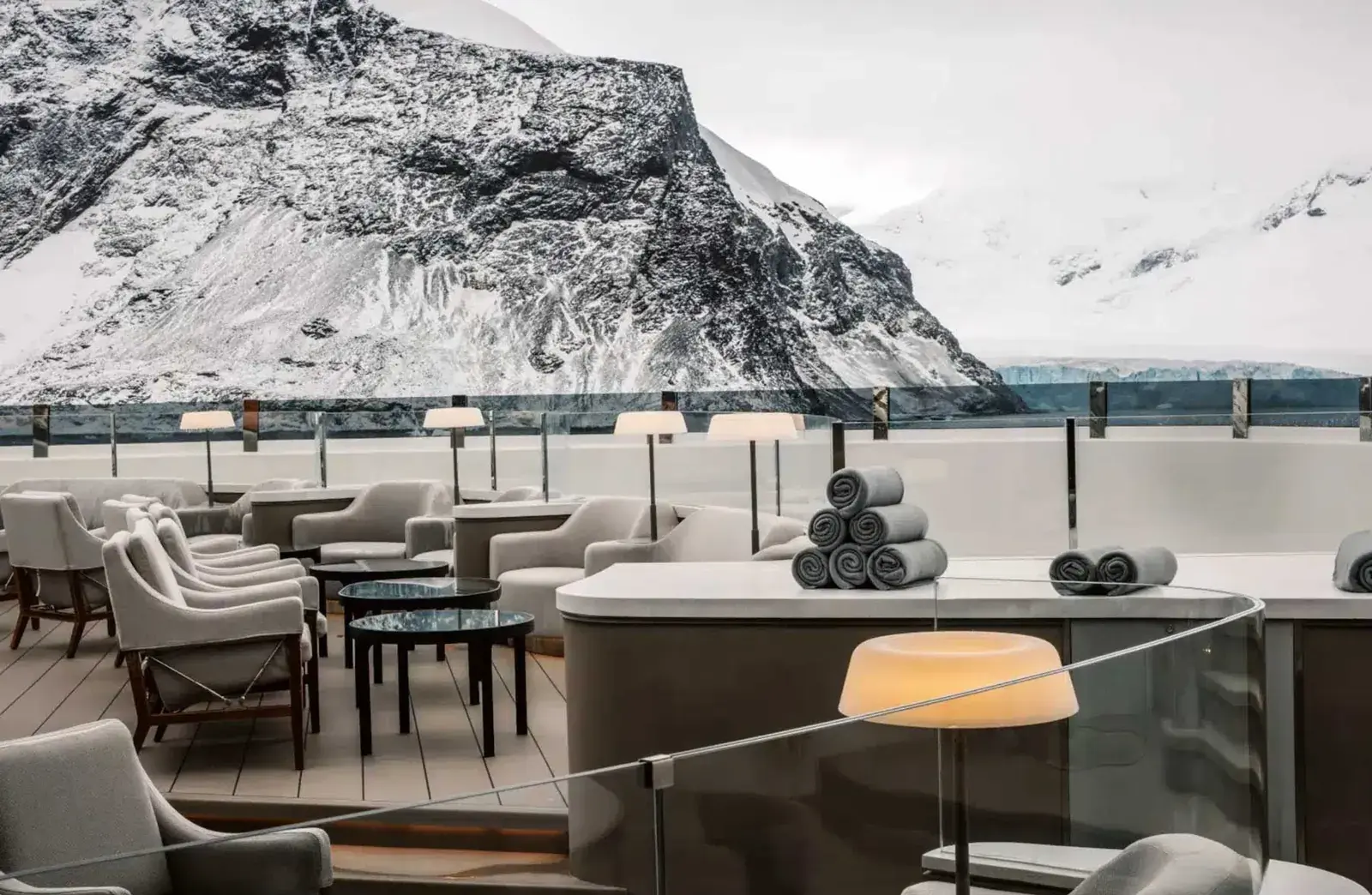 A Ponant cruise ship outdoor dining deck with polar mountains in the background