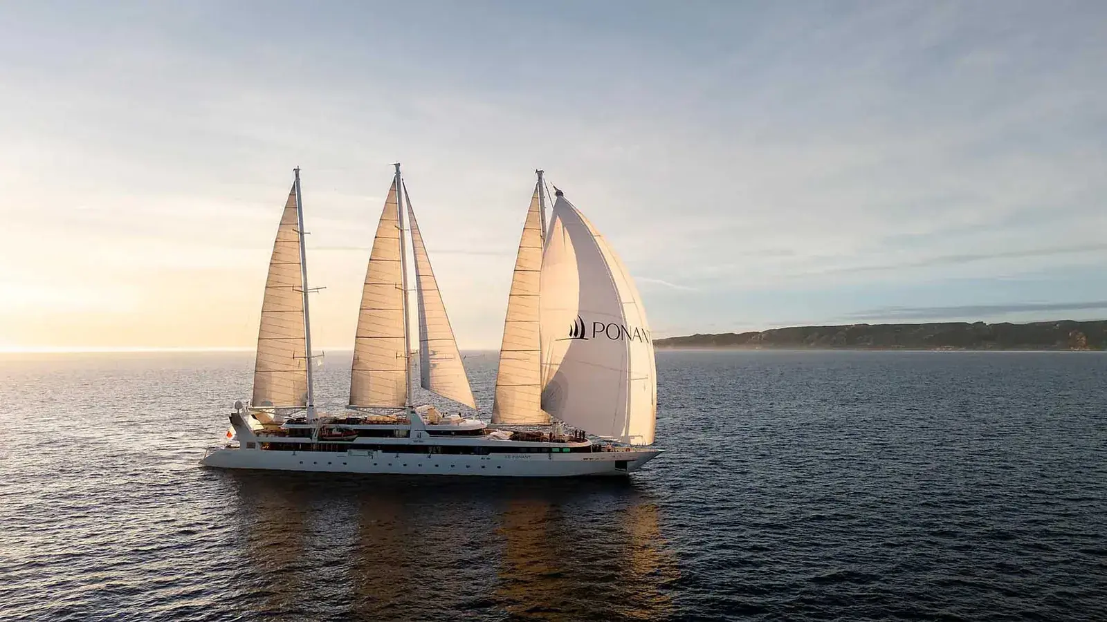 A Ponant sailboat cruise ship at sunset