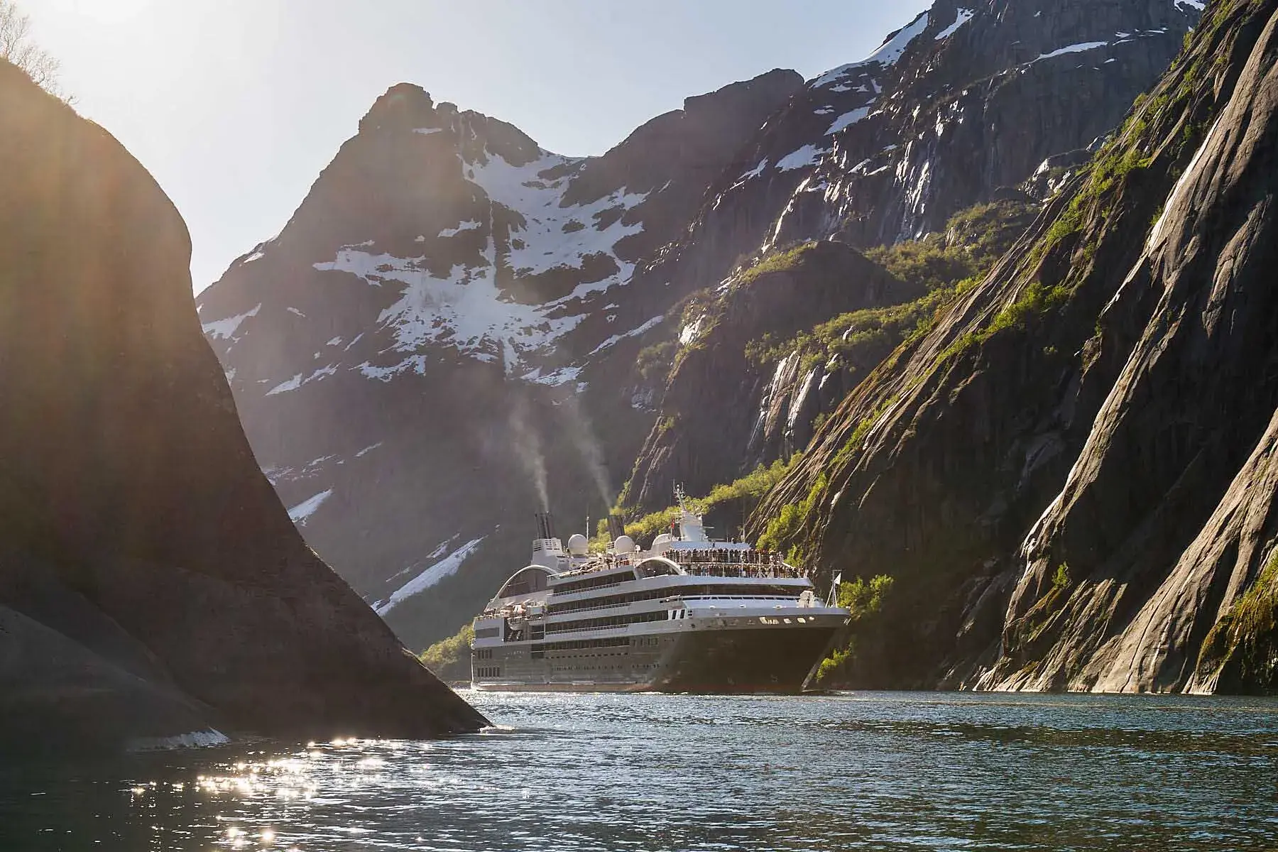 A Pondant cruise ship sails through Trollfjorden at sunset