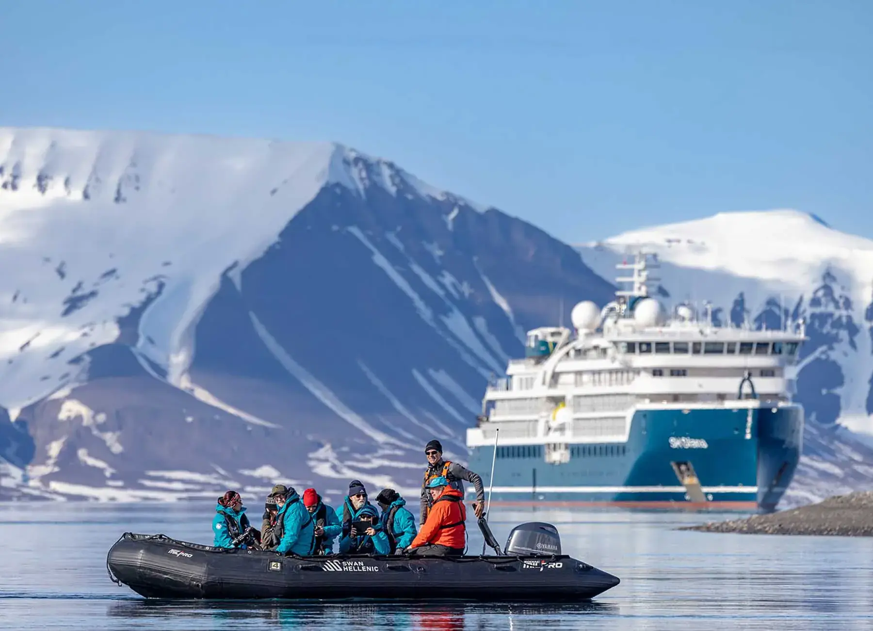 A Zodiac full of passengers cruises past a Swan Hellenic ship in Antarctica