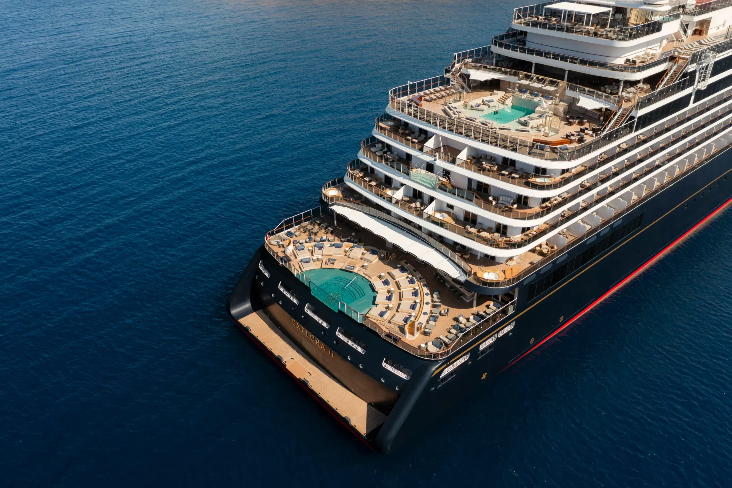 Aerial view of Explora II at anchor, pool decks stepping down to the stern