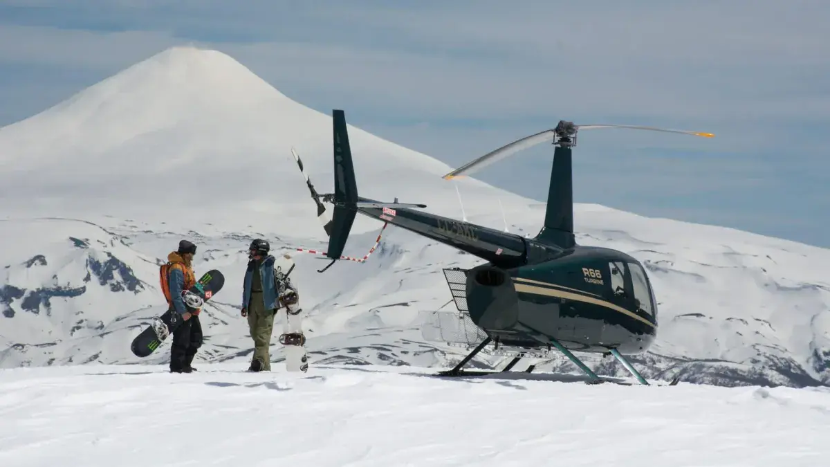 A heli-skiing helicopter dropping skiers off on a hilltop
