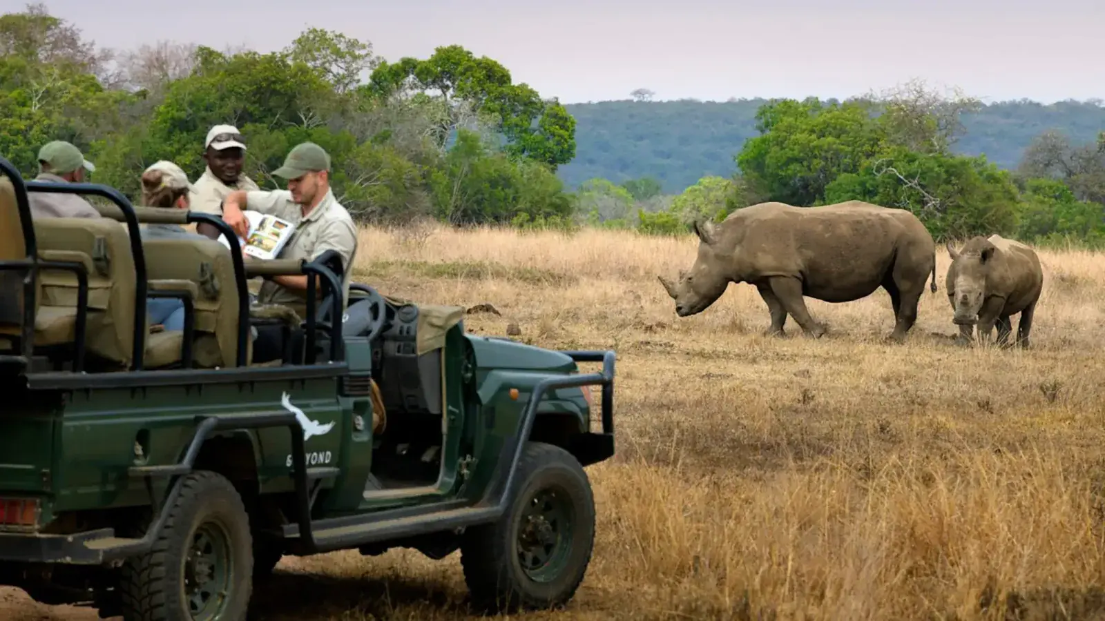 An &Beyond safari jeep next to rhinos