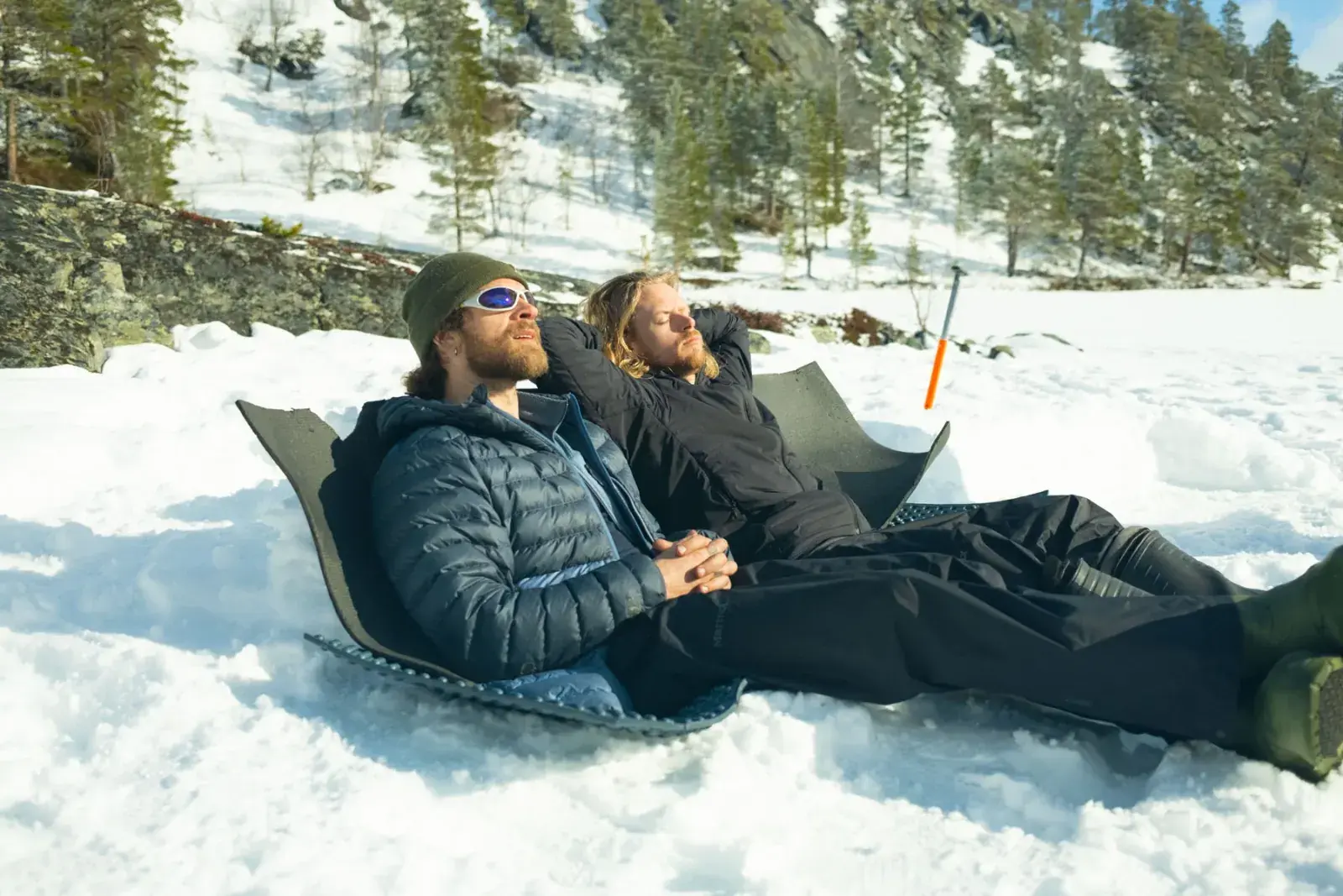 Two expedition guides relaxing in the snow on an Arctic Norway beach