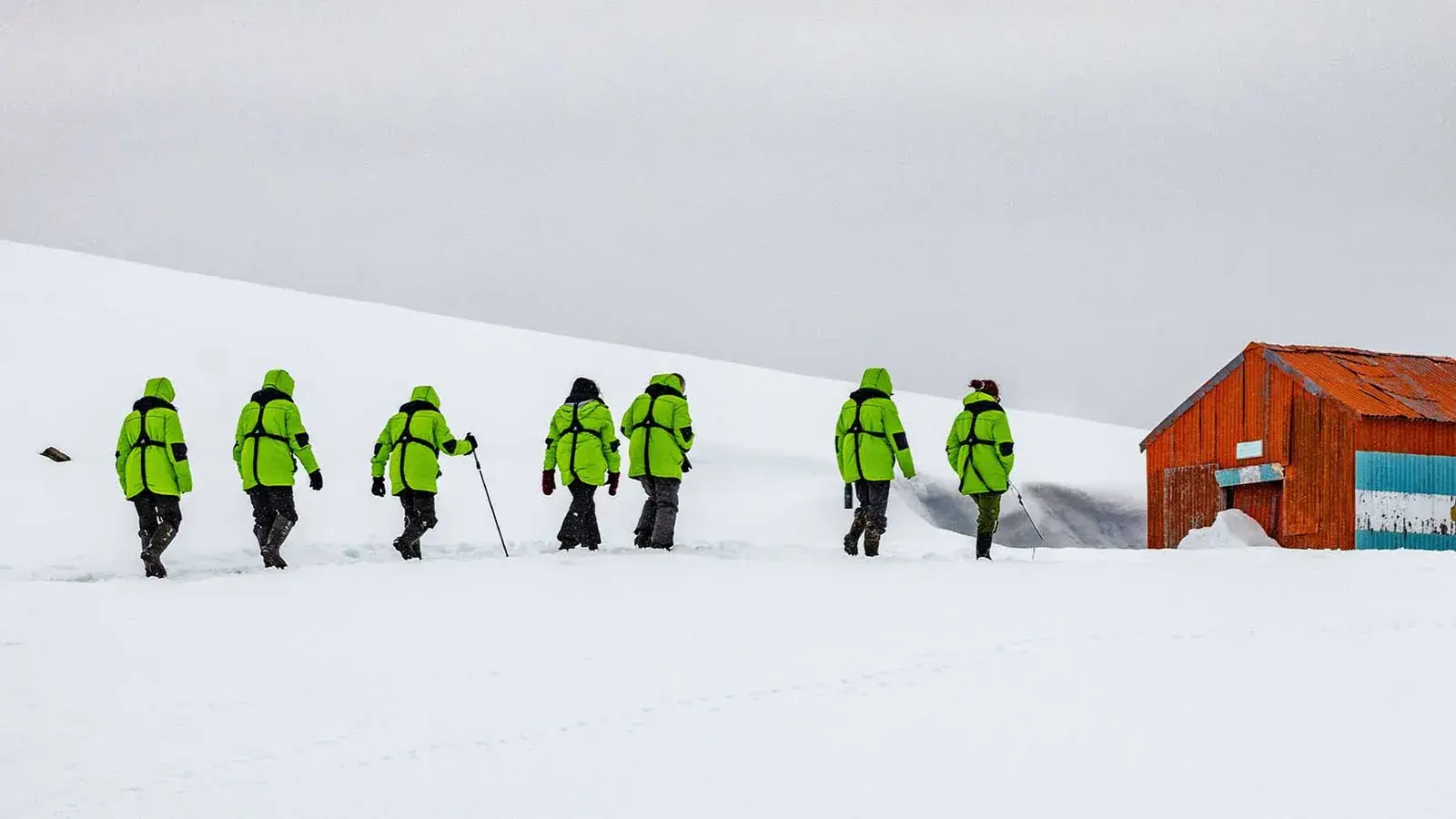Hikers walk toward an orange building in Antarctica