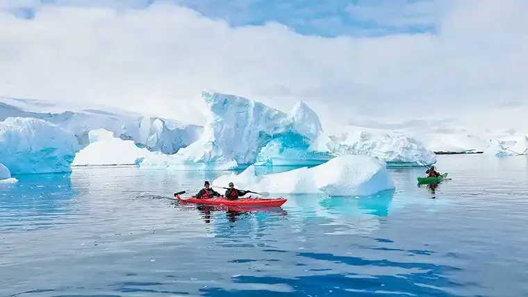 Kayaker navigate icebergs in Antartctic waters