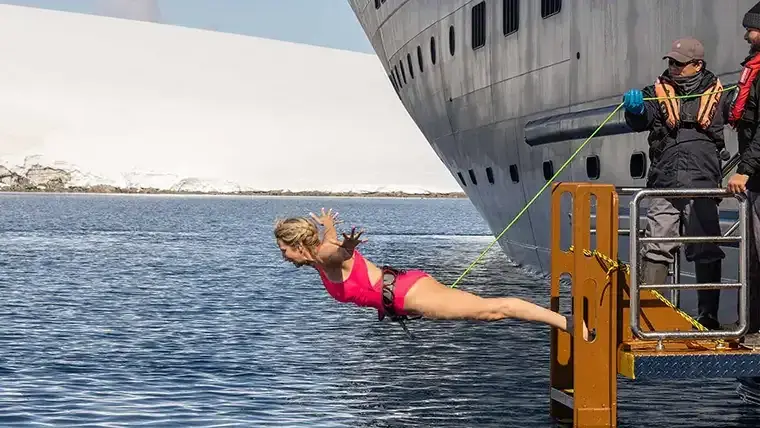 A woman takes the polar plunge off the Atlas World Navigator in Antarctica