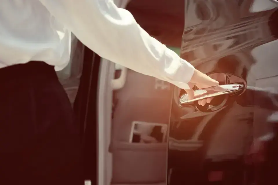 A professional driver opens the door to a car