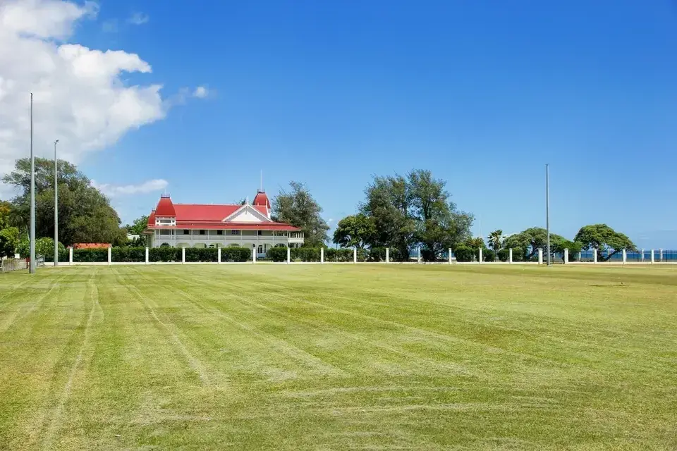 An open grass field with a red roof building in the background