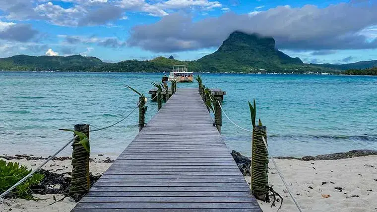 Small dock extending into a calm, crystal-clear Tahitian bay