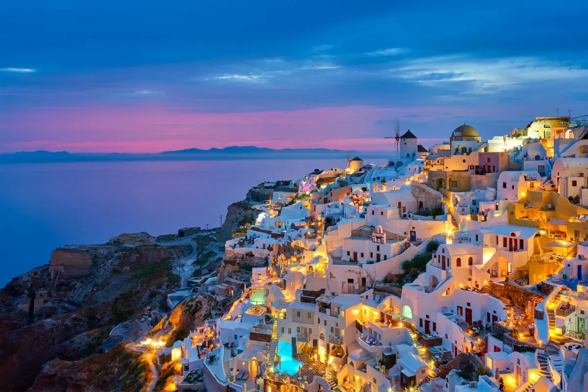 Hillside homes lit up at dusk in Santorini, Greece