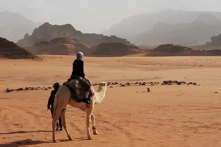 A man rides a camel through Wadi Rum in Petra, Jordan