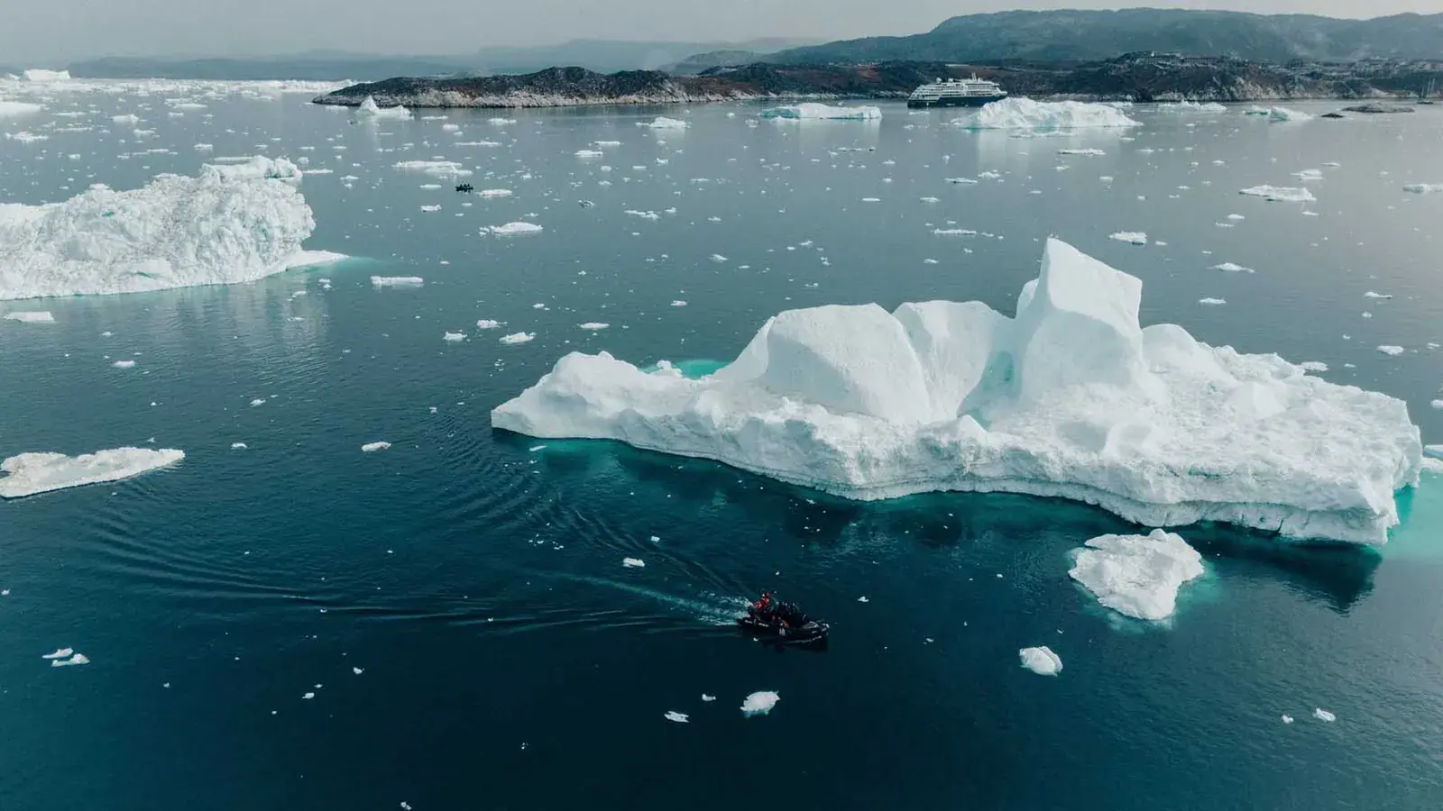 Zodiac cruising between towering icebergs in Disko Bay