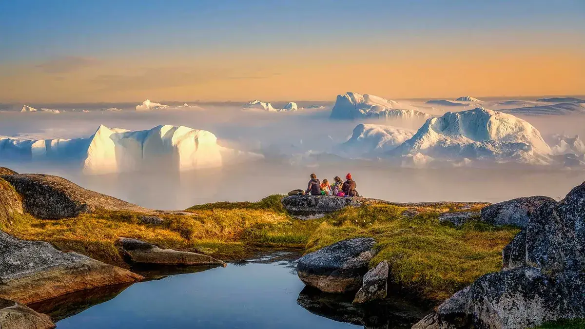Travelers gazing at Greenland peaks from a mountaintop