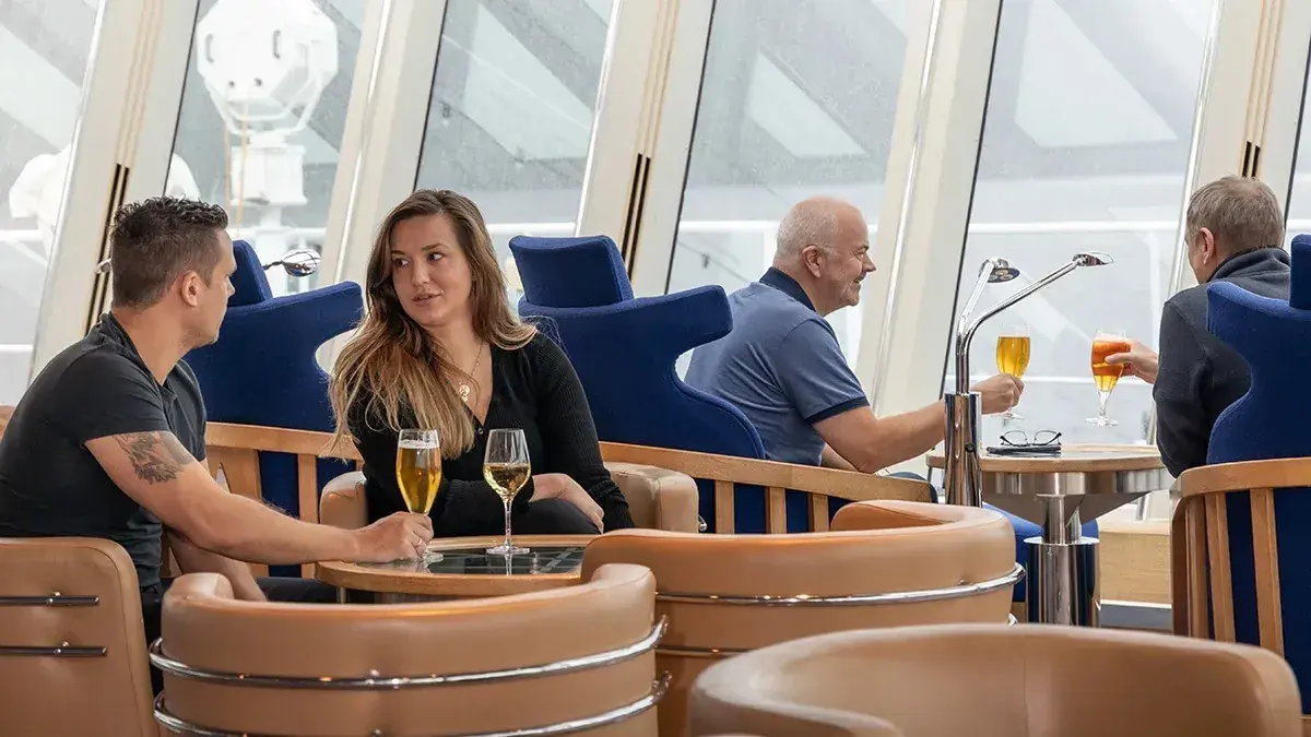 People have cocktails in the Explorer Lounge on an HX cruise ship
