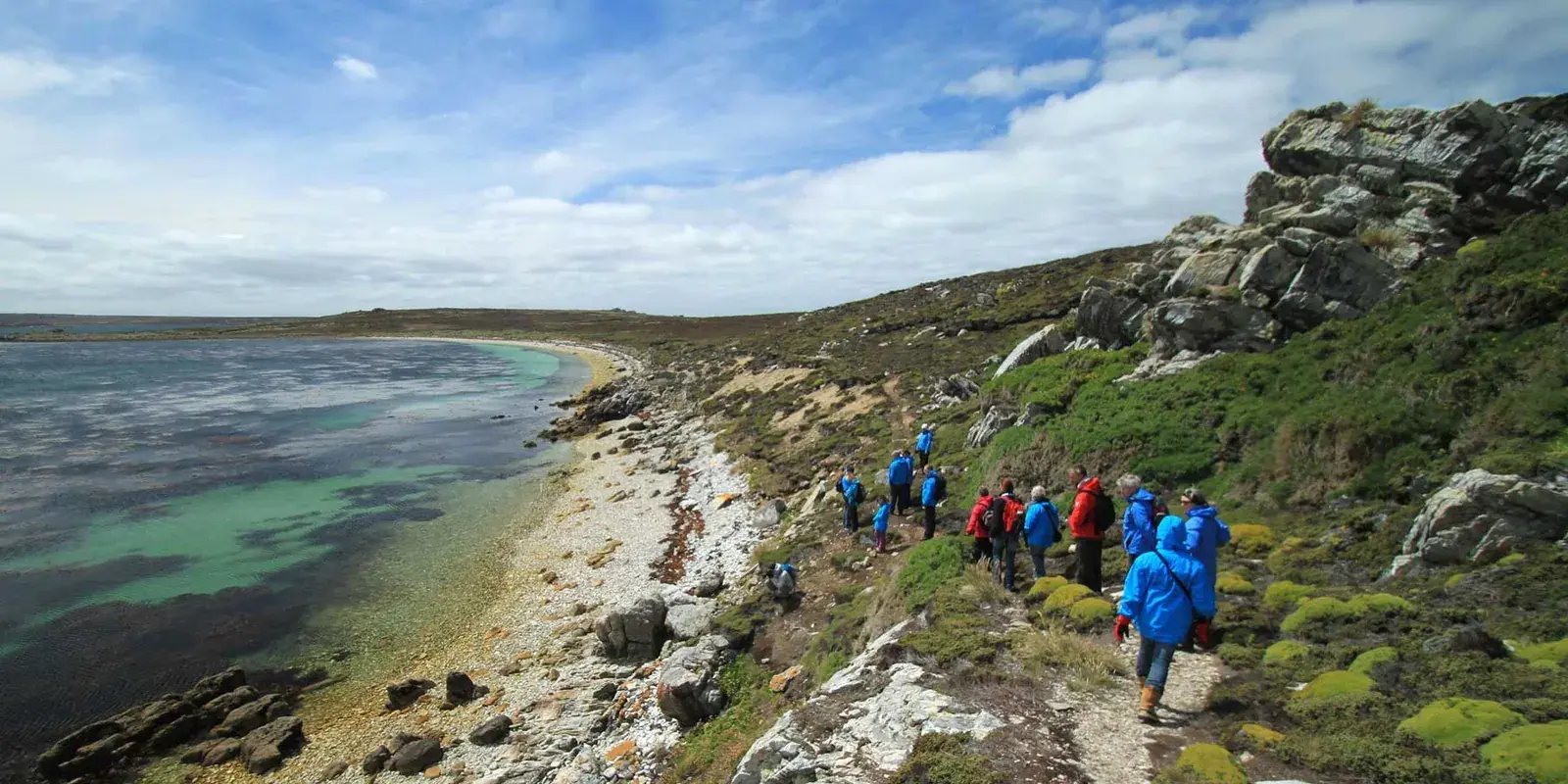Hikers hike along the ocean in the Falklands