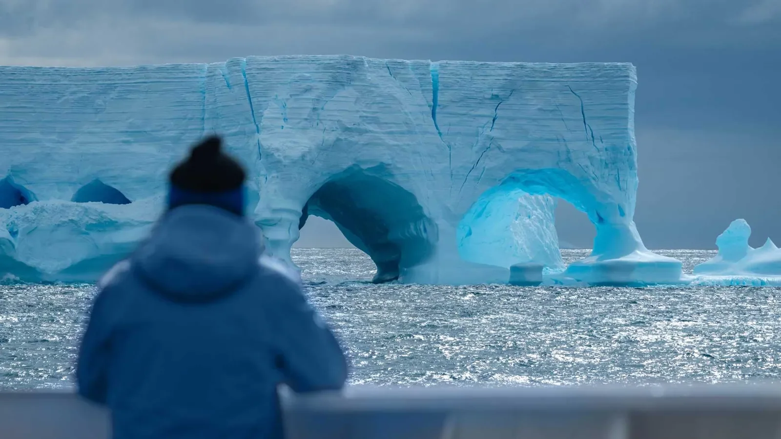 A man gazes at an iceberg in antarctica
