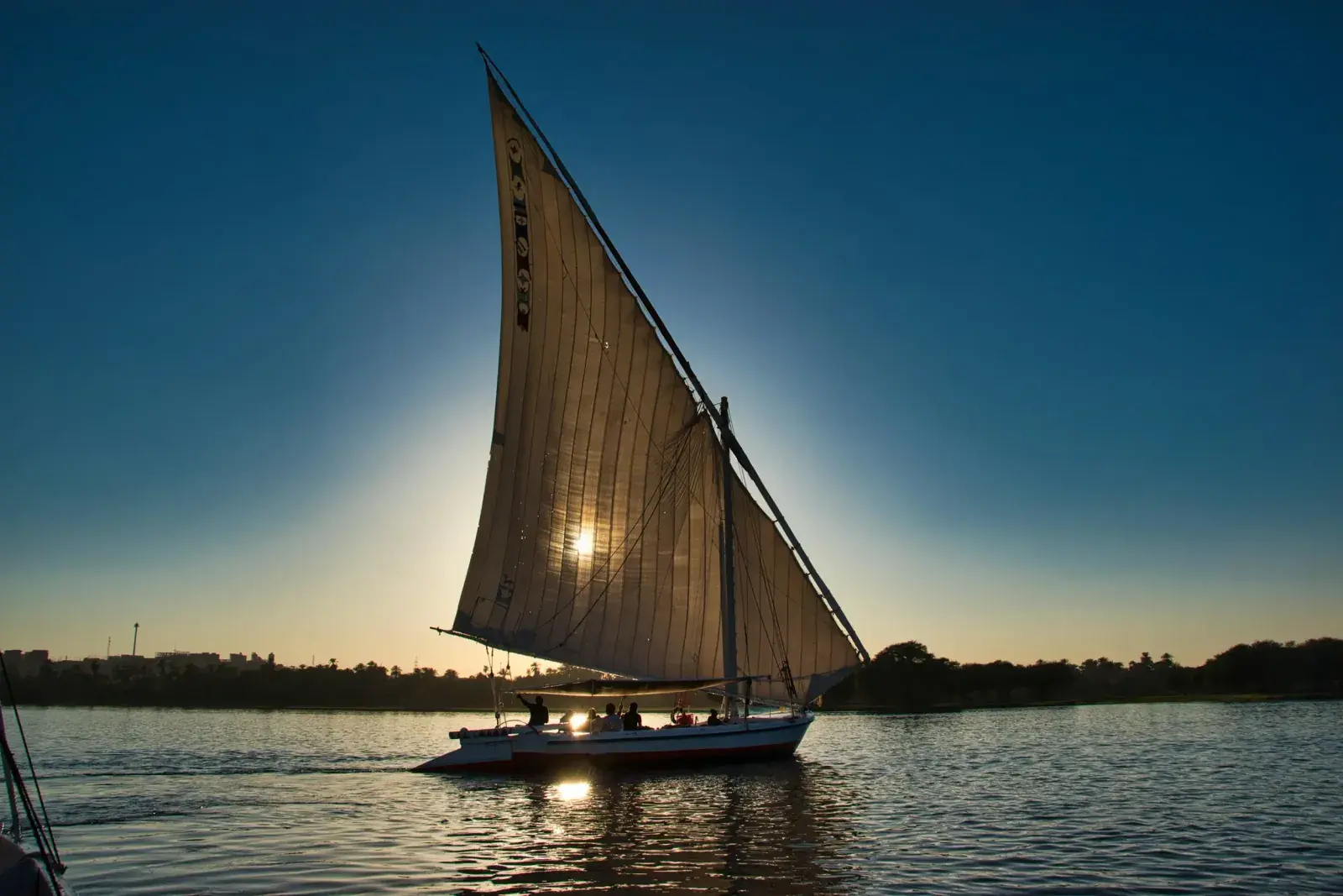 A felucca sails past the sunset on the Nile