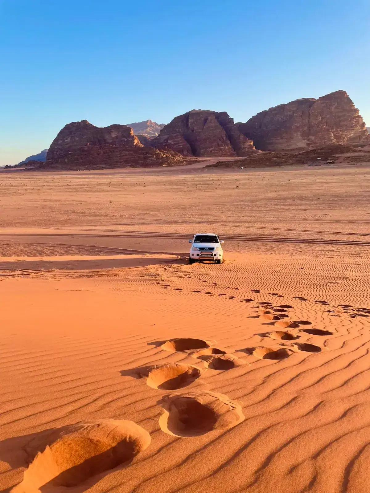 A jeep drives through the red sands of Wadi Rum, Jordan