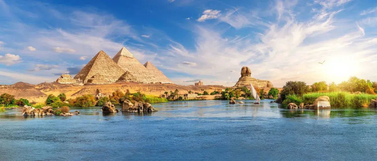Egypt's Giza Plateau with pyramids and sphinx in the background and Nile river in the foreground
