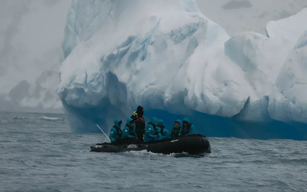 A Zodiac expedition craft passes an iceberg in Antarctica
