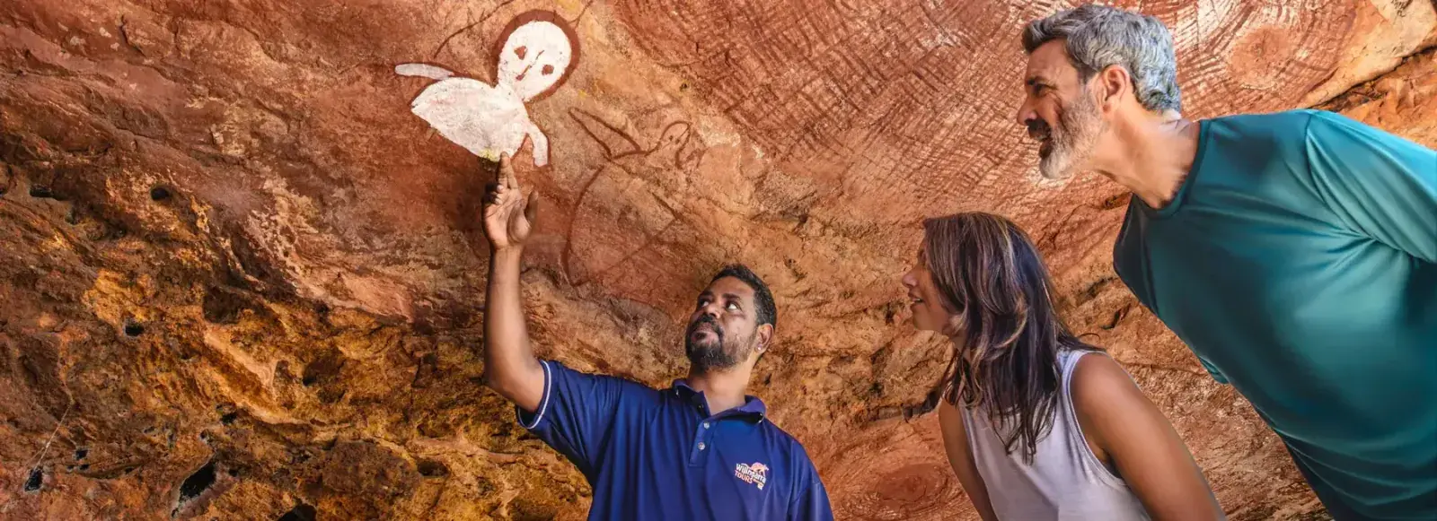 A guide points to ancient artwork in the Kimberley, Australia