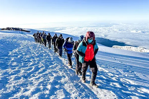 Hikers walk through snow near the summit on Kilimanjaro