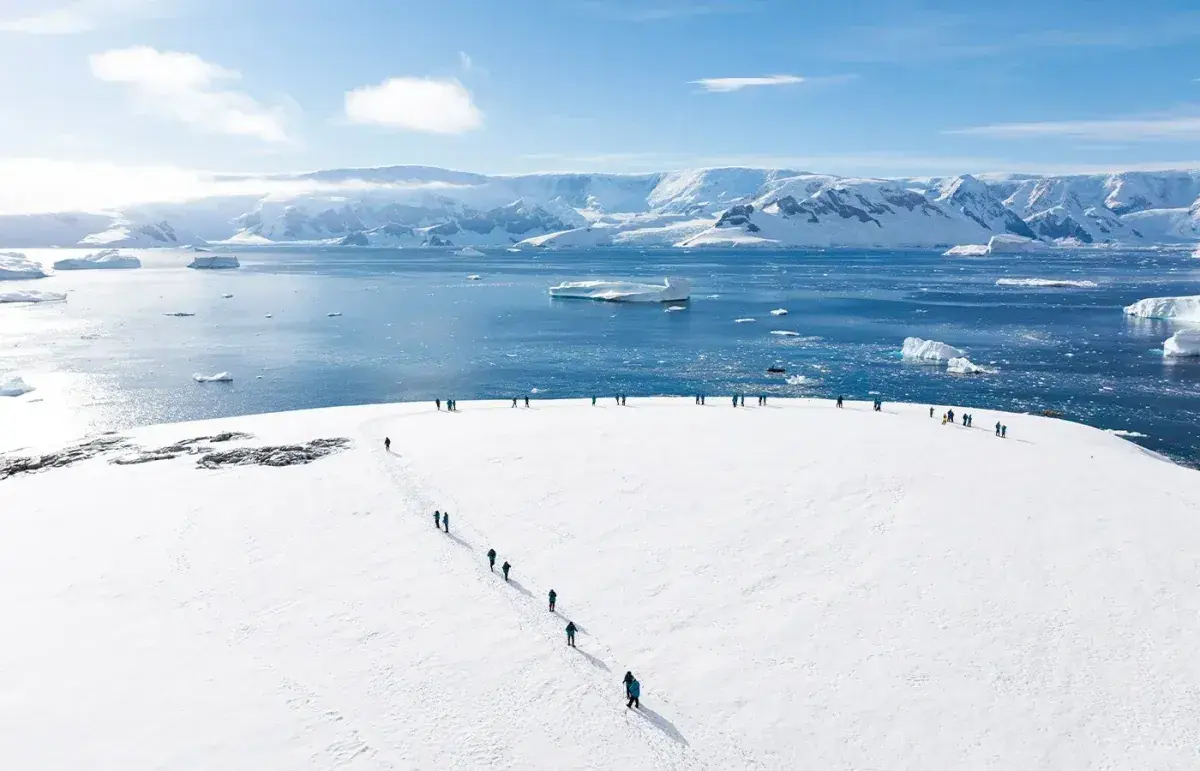 People walk across a snowy surface in Antarctica