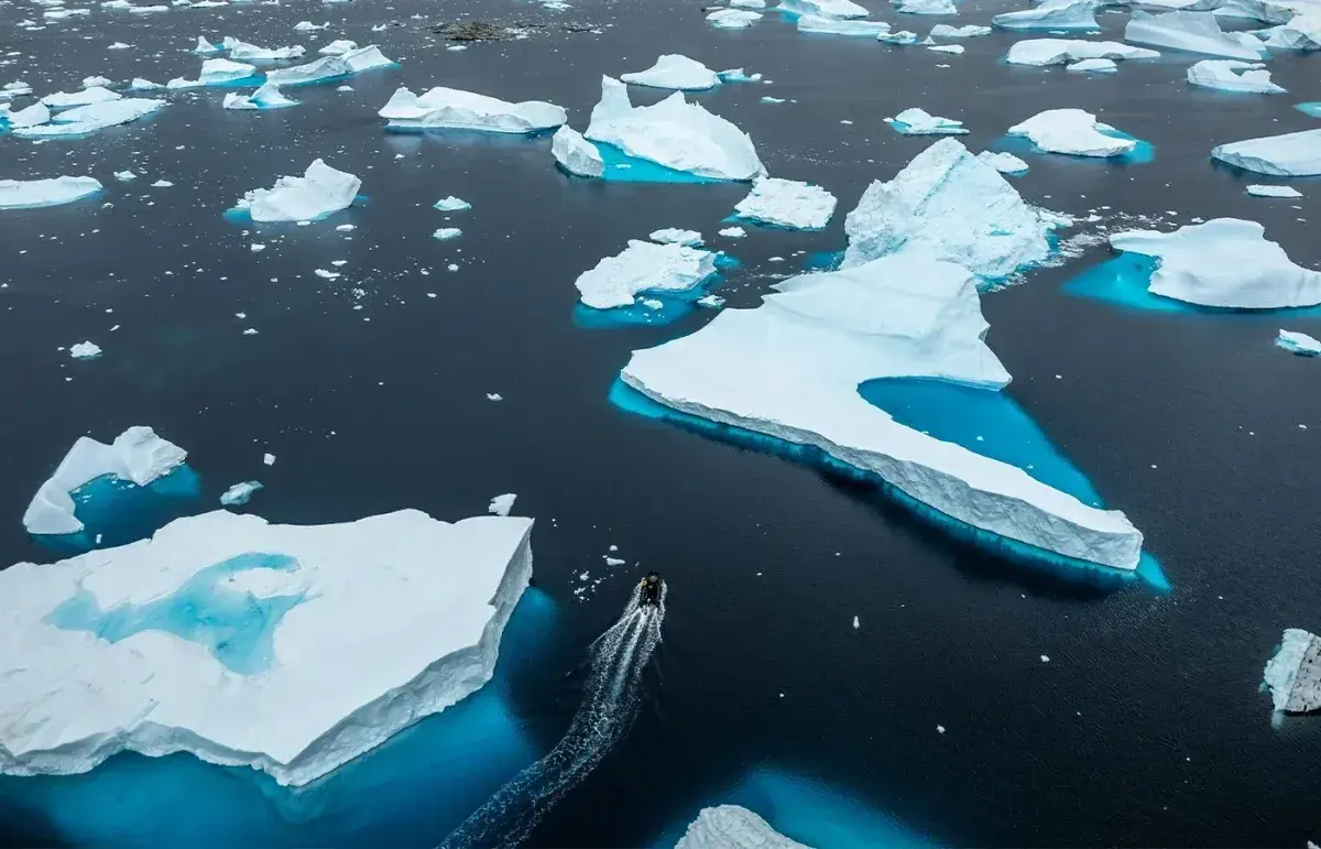 Aerial of a zodiac moving through small icebergs in Antarctica
