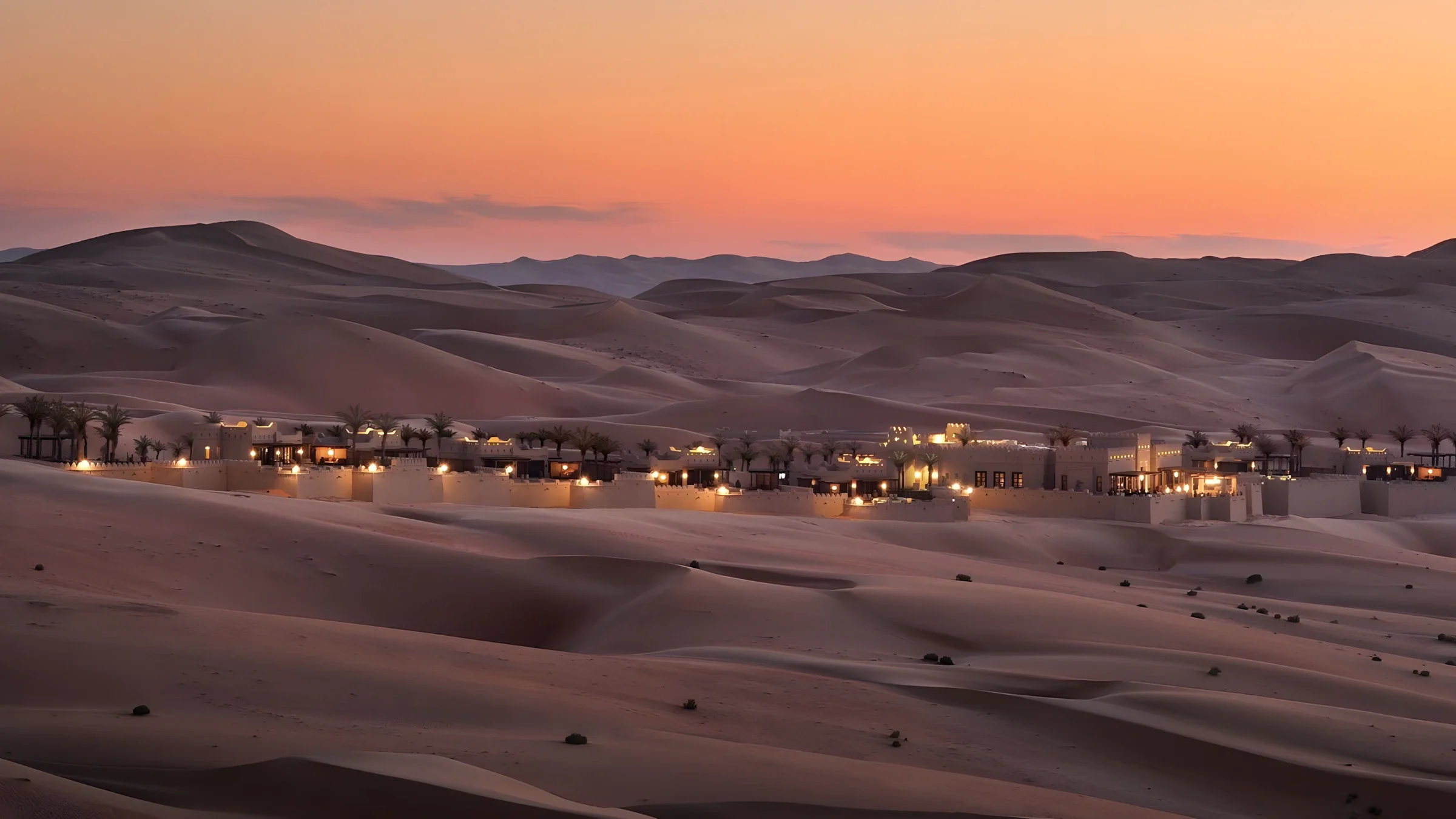 A desert resort lit at dusk among the dunes of the Empty Quarter