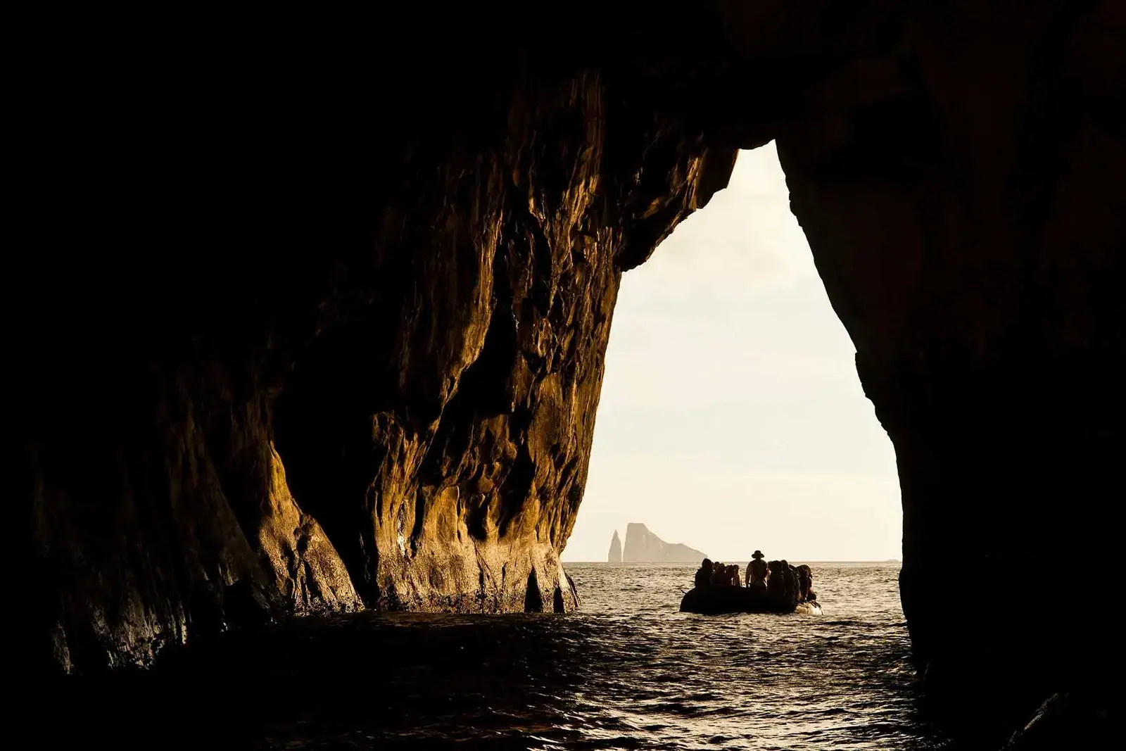 A zodiac passes through Kicker Rock in the Galapagos Islands