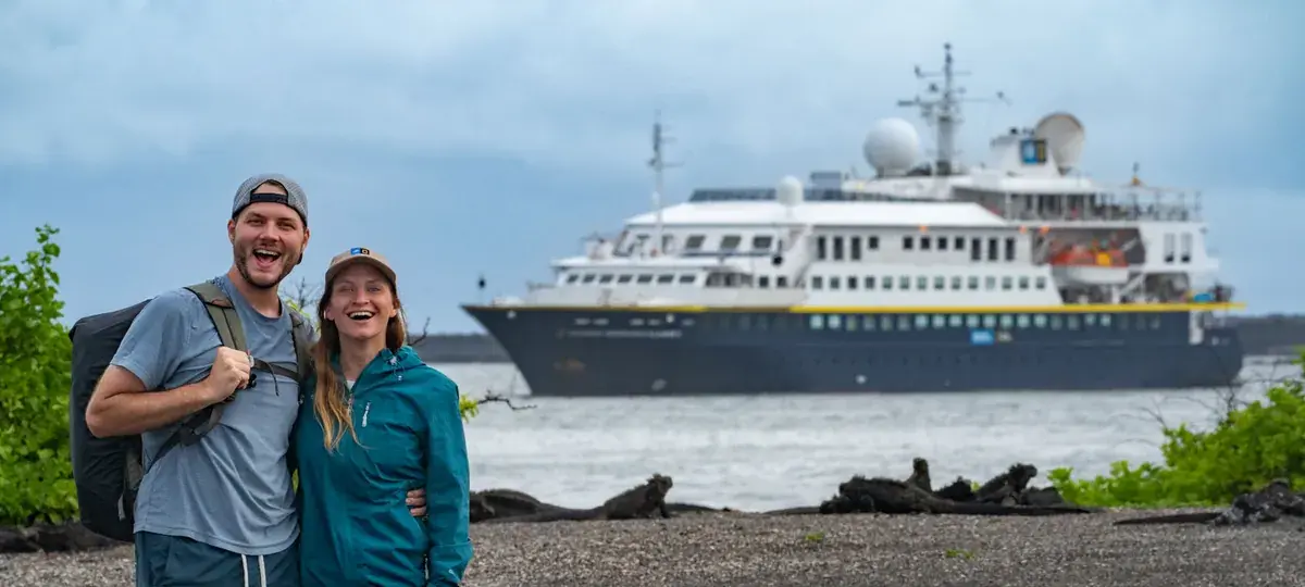 Jess and Justin from Uprooted Traveler stand in front of the National Geographic cruise ship in the Galapagos Islands