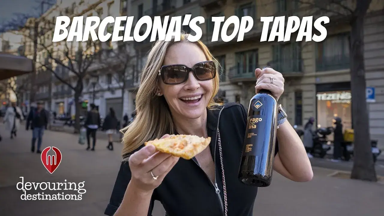 Erin Lockwood holds up a bottle of wine and a piece of food in Barcelona